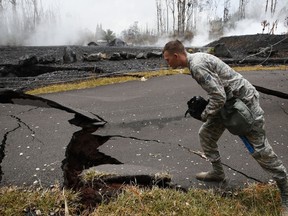 U.S. Air National Guardsman John Linzmeier looks at cracks as toxic gases rise near by in the Leilani Estates subdivision near Pahoa, Hawaii Friday, May 18, 2018.