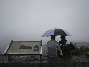 A couple sits on the edge of the Jaggar Museum's overlook to view Kilauea's summit crater in Volcanoes National Park, Hawaii, Thursday, May 10, 2018. The park is closing Friday due to the threat of an explosive volcanic eruption.