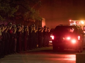 Chicago Fire Department and Chicago Police personnel salute as a procession of emergency vehicles including the ambulance carrying the body of Chicago fire department diver Juan Bucio travels to the Cook County medical examiner's office Tuesday, May 29, 2018 in Chicago. Bucio, 46, died while searching for a man who fell off a boat on the Chicago River, early Tuesday.