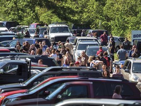 Parents wait down the road to meet their children following a shooting at Dixon High School Wednesday, May 16, 2018, in Dixon, Ill. A 19-year-old who showed up at his former high school in northern Illinois and opened fire on a police officer working there, was shot by the officer and taken into custody. The officer, who was not injured, was hailed a hero for his quick response protecting students and staff who had gathered at Dixon High School for a graduation rehearsal.