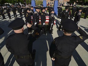 Officers with the Terre Haute Police Department and members of other agencies form a cordon to pay respect to fallen Terre Haute Police Officer Rob Pitts as his casket is carried on Tuesday, May 8, 2018, outside of Hulman Center in Terre Haute, Ind. He was killed Friday in a shootout with a homicide suspect. His funeral is set for Wednesday.