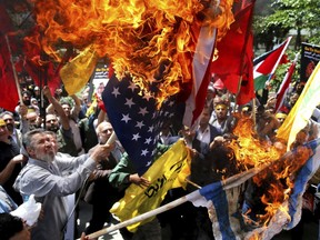 Demonstrators burn Israeli and U.S. flags to show their anger over the deaths of nearly 60 Palestinians along the Gaza border on Monday, during a protest inside the former U.S. embassy in Tehran, Iran, Wednesday, May 16, 2018.