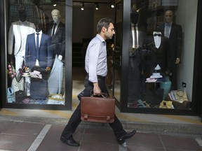 A man walks past a clothes shop in downtown Tehran, Iran, Monday, May 7, 2018. Iranian President Hassan Rouhani has seen his influence wane as his signature achievement, the nuclear deal with world powers, is now under threat from President Donald Trump. Economic problems, as well as some suggesting a military dictatorship for the country, suggest Iran's domestic politics may swing back toward hard-liners and further weaken the once-popular president.