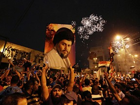 FILE - In this Monday, May 14, 2018 file photo, supporters of Shiite cleric Muqtada al-Sadr, carry his image as they celebrate in Tahrir Square, Baghdad, Iraq. Al-Sadr, who led punishing attacks on American forces after the 2003 U.S.-led overthrow of Saddam Hussein, appears set to secure the most significant victory of his political career with a strong showing in the May 12 parliamentary election. Al-Sadr gained popularity as a nationalist voice campaigning against corruption and against Iran's influence in the country.