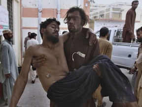 A Pakistani mine worker carries an injured colleague upon arrival at a hospital in Quetta, Pakistan, Saturday, May 5, 2018. A government official says a methane gas explosion in a coal mine has killed some miners and injured few in southwest Pakistan.