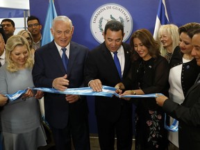 Israeli Prime Minister Benjamin Netanyahu, second left, and his wife Sara, left, and Guatemalan President Jimmy Morales, center, watch as the Guatemalan First Lady Hilda Patricia Marroquin cuts the ribbon during the dedication ceremony of the embassy of Guatemala in Jerusalem, Wednesday, May 16, 2018.