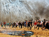 Palestinians run from tear gas during clashes with Israeli security forces near the border between Israel and the Gaza Strip on May 14, 2018. The Palestinians were protesting the U.S. embassy being moved to Jerusalem.