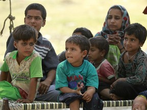 Indian children rest on a cot after being moved to a safer area following cross-border firing in Ranbir Singh Pura district of Jammu and Kashmir state, India, Tuesday, May 22, 2018. Villages along the India-Pakistan international border are almost deserted as most have moved to safer areas away from the volatile border region.