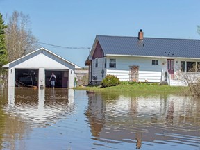 Rick Banks walks past his garage while cleaning up debris from his property located along route 105 in Maugerville, N.B, Wednesday, may 9, 2018. While water levels in Fredericton dropped to 7.15 meters Wednesday some areas still remain closed to traffic.THE CANADIAN PRESS/James West