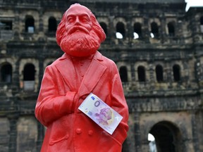 This picture taken on April, 10, 2018 in Trier, southwestern Germany, shows a red figure of German philosopher Karl Marx with a Zero-Euro-bank note released on the occasion of Marx's bicentenary.