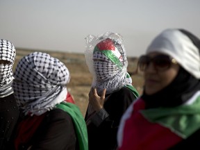 Palestinian woman wears plastic bag to protect herself from teargas fired by Israeli troops during a protest at the Gaza Strip's border with Israel, Friday, May 25, 2018.