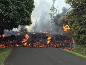 In this Sunday, May 6, 2018 photo provided by the U.S. Geological Survey,  a lava flow moves across Makamae Street in the Leilani Estates subdivision near Pahoa on the island of Hawaii. Kilauea volcano has destroyed more than two dozen homes since it began spewing lava hundreds of feet into the air last week, and residents who evacuated don't know how long they might be displaced. The decimated homes were in the Leilani Estates subdivision, where molten rock, toxic gas and steam have been bursting through openings in the ground created by the volcano. (U.S. Geological Survey via AP)