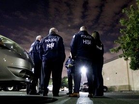 FILE - In this Jan. 10, 2018, file photo U.S. Immigration and Customs Enforcement agents gather before serving a employment audit notice at a 7-Eleven convenience store in Los Angeles. Immigration officials have sharply increased audits of companies to verify that their employees are authorized to work in the country, signaling the Trump administration's crackdown on illegal immigration is reaching deeper into the workplace to create a "culture of compliance" among employers who rely on immigrant labor.