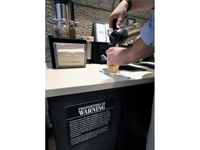 FILE - In this Friday, Sept. 22, 2017, file photo, a customer pours milk into coffee near a posted Proposition 65 warning sign at a Starbucks coffee shop in Los Angeles. In a long-running court case playing out in a Los Angeles courtroom, a nonprofit has been presenting evidence to show that coffee companies should post ominous warning labels about a cancer-causing chemical in every cup. Los Angeles Superior Court Judge Elihu Berle issued his final decision Monday, May 7, 2018, that Starbucks and other coffee companies failed to show that benefits from drinking coffee outweighed any risks.