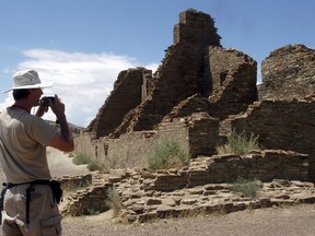 FILE - In this Aug. 10, 2005, file photo, tourist Chris Farthing from Suffolks County, England, takes a picture of the Chaco Canyon ruins while visiting the park in Chaco Canyon, N.M. Oil and gas drilling on tens of thousands of acres surrounding a national park in northwestern New Mexico would be prohibited under legislation introduced by two U.S. senators. The effort to establish a "protection zone" around Chaco Culture National Historical Park is the latest salvo in a long-running battle among developers and environmental and tribal interests.