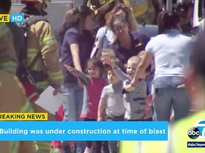 In this photo taken from video provided by KABC-TV, children are evacuated from a preschool across the street from a building that was rocked by an explosion in Aliso Viejo, Calif., Tuesday afternoon, May 15, 2018. None of these children were hurt. Authorities say one person is dead and several others have injuries. The cause of the blast is being investigated.  (KABC-TV via AP)