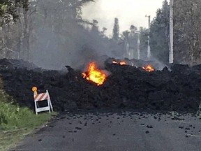 This photo provided by Hawaii Electric Light shows lava flowing over Mohala Street in the Leilani Estates area near Pahoa on the Big Island of Hawaii Friday, May 4, 2018. Nearly 1,500 people have fled from their homes after Hawaii's Kilauea volcano sent molten lava chewing through forests and bubbling up on paved streets in an eruption that one resident described as "a curtain of fire." (Hawaii Electric Light via AP)