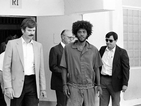 FILE - In this July 31, 1983, file photo, Kevin Cooper, center, a suspect in connection with the slashing death of four people in Chino, is escorted to a car for transport to San Bernadino from Santa Barbara, Calif., after he was arrested by police at Santa Cruz Island. U.S. Sen. Kamala Harris says California's governor should allow advanced DNA testing that advocates say could exonerate a death row inmate, Friday, May 18, 2018. The 60-year-old inmate was convicted of the 1983 Los Angeles-area hatchet and knife killings of four people. Kevin Cooper's clemency request is being reviewed by Gov. Jerry Brown's office. Two previous DNA tests concluded Cooper was the killer. California hasn't executed anyone since 2006. (AP Photo/File)