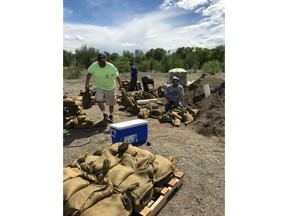 In this Thursday, May 10, 2018 photo provided by the Colville Tribes Environmental Trust Program, tribal members fill sandbags in Omak, Wash. The Okanogan River, which runs through Tonasket, reached a level of 19 feet (5.8 meters) early Friday morning, which is above the 15-foot (4.6-meter) flood stage. Officials with the U.S. Army Corps of Engineers and Okanogan County Emergency Management are continuing to monitor river levels.