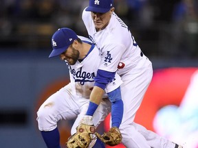 Los Angeles Dodgers shortstop Chris Taylor, left, and second baseman Chase Utley collide as they try to field a ball hit by Cincinnati Reds' Jose Peraza during the sixth inning of a baseball game Friday, May 11, 2018, in Los Angeles. Utley ended up with the ball and forced out Jesse Winker at second.