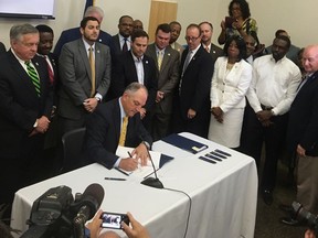 FILE - In this June 15, 2017, file photo, a bipartisan group of lawmakers surround Louisiana Gov. John Bel Edwards as he signs 10 criminal justice bills into law during a ceremony in Baton Rouge, La. Months after a heavily hyped overhaul of Louisiana's criminal justice codes, lawmakers have introduced a flurry of proposals to walk back some of the changes.