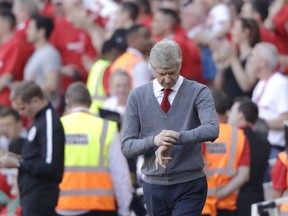 Arsenal's French manager Arsene Wenger looks at his watch after his side scored the fifth goal during the English Premier League soccer match between Arsenal and Burnley at the Emirates Stadium in London, Sunday, May 6, 2018. The match is Arsenal manager Arsene Wenger's last home game in charge after announcing in April he will stand down as Arsenal coach at the end of the season after nearly 22 years at the helm.