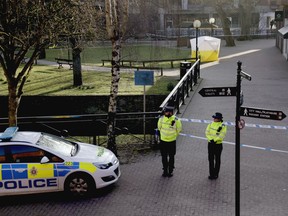 FILE - In this Wednesday, March 7, 2018 file photo, police officers guard a cordon around a police tent covering the the spot where former Russian double agent Sergei Skripal and his daughter were found critically ill following exposure to an "unknown substance" in Salisbury, England. Doctors who treated poisoned ex-spy Sergei Skripal and his daughter Yulia say they don't know what their long-term prognosis is. The pair were found unconscious in the English city of Salisbury March 4 after being exposed to a nerve agent known as Novichok.