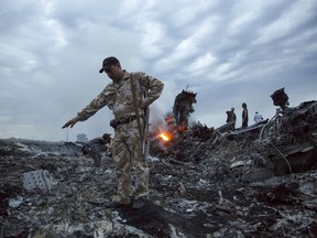 FILE - In this July 17, 2014. file photo, people walk amongst the debris at the crash site of a passenger plane near the village of Grabovo, Ukraine. An international team of investigators says that detailed analysis of video images has established that the Buk missile that brought down Malaysia Airlines Flight 17 nearly four years ago came from a Russia-based military unit. Wilbert Paulissen of the Dutch National Police said Thursday, May 24, 2018 that the missile was from the Russian military's 53rd anti-aircraft missile brigade based in the Russian city of Kursk.