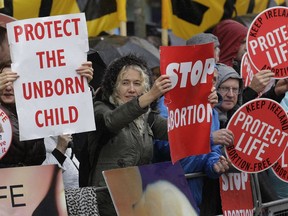 FILE - In this Thursday, Oct. 18, 2012 file photo, protesters opposed to abortion hold placards outside the Marie Stopes clinic in Belfast, Northern Ireland. Britain's leaders are facing increasing calls to take action to loosen abortion restrictions in Northern Ireland after the Republic of Ireland's vote in favor of doing so, but complex political realities make quick action difficult. Prime Minister Theresa May is being asked by some legislators and activists to take steps that might lead to liberalization in the Northern Ireland now that Ireland has voted overwhelmingly to repeal its constitutional ban.