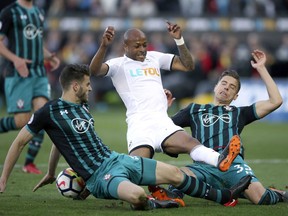 Swansea City's Andre Ayew battles for the ball with Southampton's Jan Bednarek, right, and Wesley Hoedt during the English Premier League soccer match at the Liberty Stadium, Swansea, Wales, Tuesday May 8, 2018.