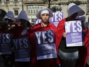 Volunteers from Reproductive rights, against Oppression, Sexism & Austerity (ROSA) dressed as characters from 'The Handmaid's Tale', demonstrate in Dublin, Wednesday May 23, 2018, calling for a 'Yes' vote in Ireland's upcoming abortion referendum on Friday.