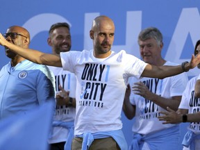 Manchester City soccer team manager Pep Guardiola acknowledges supporters during the British Premier League champions trophy parade in Manchester, England, Monday May 14, 2018.  Manchester City soccer team paraded through the streets of Manchester aboard open top buses, celebrating winning the Premier League title by a record 19 points.