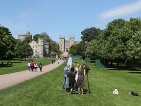 British TV presenter Amanda Holden, centre of group, filming for the US television show Inside Edition, on the Long Walk in Windsor, England, Monday May 14, 2018, ahead of the May 19 wedding of Britain's Prince Harry and Meghan Markle.  Worldwide media outlets begin setting up for their coverage of the marriage upcoming weekend, reporting from the town of Windsor, which is dominated by the castle keep, seen at far background left.