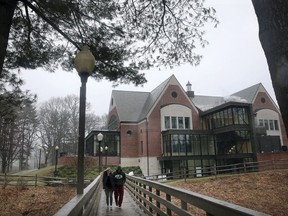 In this April 6, 2018 photo, students walk on the campus of Mount Ida College in Newton, Mass. The state attorney general's office said Tuesday, May 15, 2018, that the sale of the college to the University of Massachusetts-Amherst can proceed because UMass paid fair market value for the smaller school, and the only alternative was the bankruptcy and closure of Mount Ida.