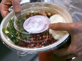 A customer carries away a prepared lunch bowl at Spyce, a restaurant which uses a robotic cooking process in Boston, Thursday, May 3, 2018. Robots can't yet bake a souffle or fold a burrito, but the new restaurant in Boston is employing what it calls a "never-before-seen robotic kitchen" to cook up ingredients and spout them into a bowl.