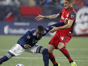 Toronto FC's Jay Chapman (14) battles New England Revolution's Luis Caicedo for the ball during the first half of an MLS soccer game in Foxborough, Mass., Saturday, May 12, 2018.