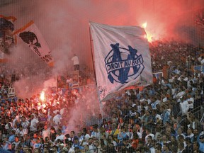 Marseille supporters burn flares and hold flags during the League One soccer match between Marseille and Amiens at the Velodrome stadium, in Marseille, southern France, Saturday, May 19, 2018.