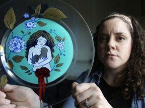 In this Thursday, April 26, 2018, photo, artist Ashley MacLure holds her painting "The Dream" created from acrylic paint and color marker on a glass plate, at her home in Milford, Mass. The blank space at the center is meant to represent the absence of a child due to a miscarriage. MacLure hopes her paintings, inspired by miscarriage, will help end the stigma of pregnancy loss.