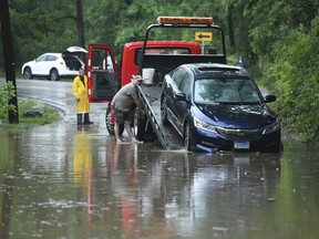 A car is being towed off of Ruxton Road in Towson, Md., Sunday, May 27, 2018. Flash flooding and water rescues are being reported in Maryland as heavy rain soaks much of the state.
