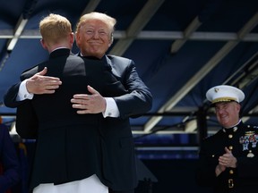 President Donald Trump embraces the last graduate in line during a graduation and commissioning ceremony at the U.S. Naval Academy, Friday, May 25, 2018, in Annapolis, Md.