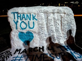 FILE - In this Jan. 26, 2018, file photo, the shadows of Michigan State University students appear on "the rock" in the university campus which was painted "Thank You" and includes the names of the women who gave victim impact statements during the Larry Nassar sexual assault sentencing hearing in East Lansing, Mich. Michigan State University announced  Wednesday, May 16, 2018, that it has reached a $500 million settlement with hundreds of women and girls who say they were sexually assaulted by sports Nassar in the worst sex-abuse case in sports history.