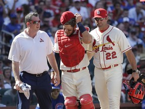 St. Louis Cardinals trainer Chris Conroy, left, and manager Mike Matheny (22) take catcher Yadier Molina back to the dugout after Molina was injured on a pitch during the ninth inning of a baseball game against the Chicago Cubs, Saturday, May 5, 2018, in St. Louis.