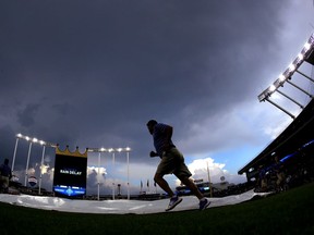 Grounds crew members pull a tarp off the field after a rain delay before a baseball game between the Kansas City Royals and the Minnesota Twins on Tuesday, May 29, 2018, in Kansas City, Mo.