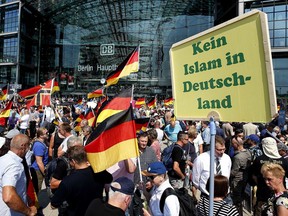Supporters of German AfD wave flags in front of the train station in Berlin, Germany, Sunday, May 27, 2018. The AfD that swept into Parliament last year on a wave of anti-migrant sentiment is staging a march Sunday through the heart of Berlin to protest against the government. Poster reads "no Islam in Germany".