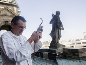 In this Monday, May 14, 2018 photo beekeeper Uwe Marth prepares his beekeeper's pipe, at the roof of the Berlin Cathedral,  a neo-baroque landmark, tourist magnet and home to perhaps 30,000 bees in the German capital Berlin.