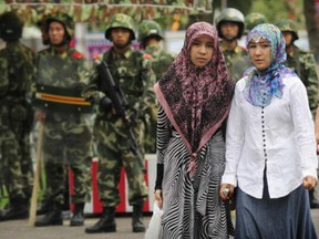 Two ethnic Uighur women pass Chinese paramilitary policemen standing guard outside the Grand Bazaar in the Uighur district of the city of Urumqi in China's Xinjiang region on July 14, 2009.