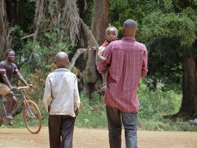 In this photo taken Tuesday, March 13, 2018, James Seferino, 11, left, walks with his father Andrea Seferino, right, both of whom are HIV-positive, while his father carries his baby son who has not got the virus after receiving treatment for HIV at a Doctors Without Borders clinic outside the town of Yambio, in South Sudan. South Sudan's five-year civil war is quietly creating another kind of victim - those prevented from accessing life-saving antiretroviral medicine, and experts say the number of affected people could be in the hundreds of thousands.