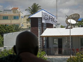 A Somali man looks out from a nearby building at the compound of the International Committee of the Red Cross (ICRC) in Mogadishu, Somalia, Thursday, May 3, 2018. Armed gunmen stormed into the ICRC compound in Somalia's capital and abducted a female staffer, the aid group said Wednesday night, and a senior police official said the nurse was German.