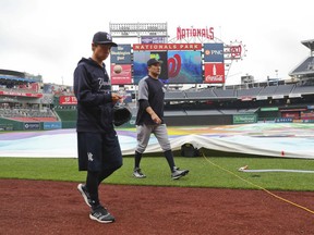 New York Yankees starting pitcher Masahiro Tanaka, center, and his translator, Shingo Horie, left, walk off the field at Nationals Park after it was announced that both of today's interleague baseball games against the Washington Nationals have been postponed due to inclement weather, Wednesday, May 16, 2018, in Washington. Both game have been rescheduled for June 18, 2018.