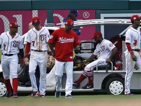 Washington Nationals second baseman Wilmer Difo, left, shortstop Trea Turner, manager Dave Martinez, and center fielder Michael Taylor, right, walk away as left fielder Howie Kendrick is taken away on the cart after an injury in the eighth inning of the first baseball game of a doubleheader against the Los Angeles Dodgers at Nationals Park, Saturday, May 19, 2018, in Washington. The Dodgers won the first game 4-1.